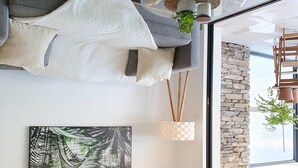Una sala de estar moderna con un sofá, un ventanal grande, una lámpara colgante y una pared de piedra.