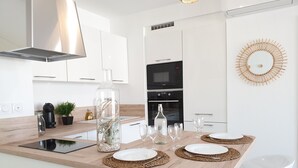 Una cocina moderna con armarios blancos, horno empotrado y una isla central con una botella de vidrio y copas de vino.