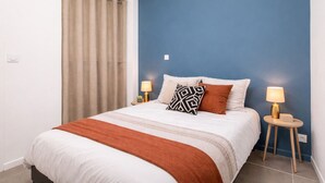 A bedroom with a bed, two bedside lamps, a window with curtains, and a blue accent wall. - Modern apartment with 40m² terrace - Extremely practical (Arras)