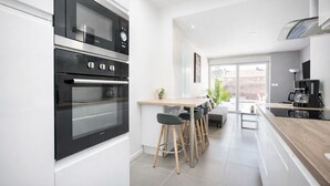 A modern kitchen with a built-in oven, a coffee machine, and a dining area with stools. - Modern apartment with 40m² terrace - Extremely practical (Arras)