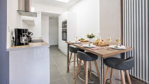 A modern kitchen with a dining area, featuring a coffee machine, a microwave, and a dining table set for two with glasses of wine. - Modern apartment with 40m² terrace - Extremely practical (Arras)