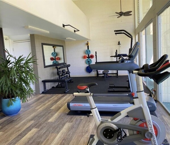 Un gimnasio con equipo de cardio, máquinas de pesas y una cinta de correr.
