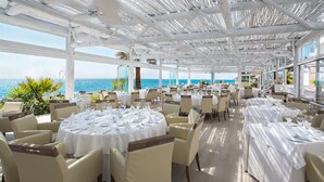 Un área de comedor al aire libre con mesas dispuestas para los huéspedes, con vista al mar.