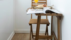 A corner room with a wooden chair, a table with a magazine, a glass of orange juice, and two hanging planters. - The Iron Artist Studio Atelier (Lisboa)