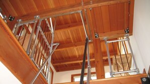 Un interior de fusta amb escales metàl·liques i bigues.