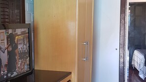 A room with wooden cabinets, a black countertop, and a television. - Casa do Sassá - Close to everything (Guarda do Embaú)