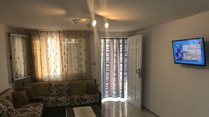 Uma sala de estar com sofá, mesa de centro e TV fixada na parede.