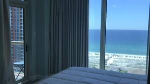 Ein Schlafzimmer mit einem großen Bett, Meerblick und einem Balkon mit Tisch und Stühlen.
