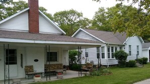 A row of single-story houses with attached porches, each with a small front yard and a pathway leading to the entrance. - House steps from the beach. (Pentwater)