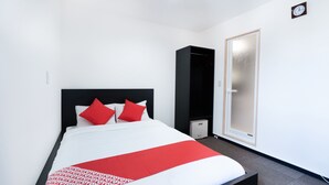Een hotelkamer met een bed, een kledingkast en een deur.