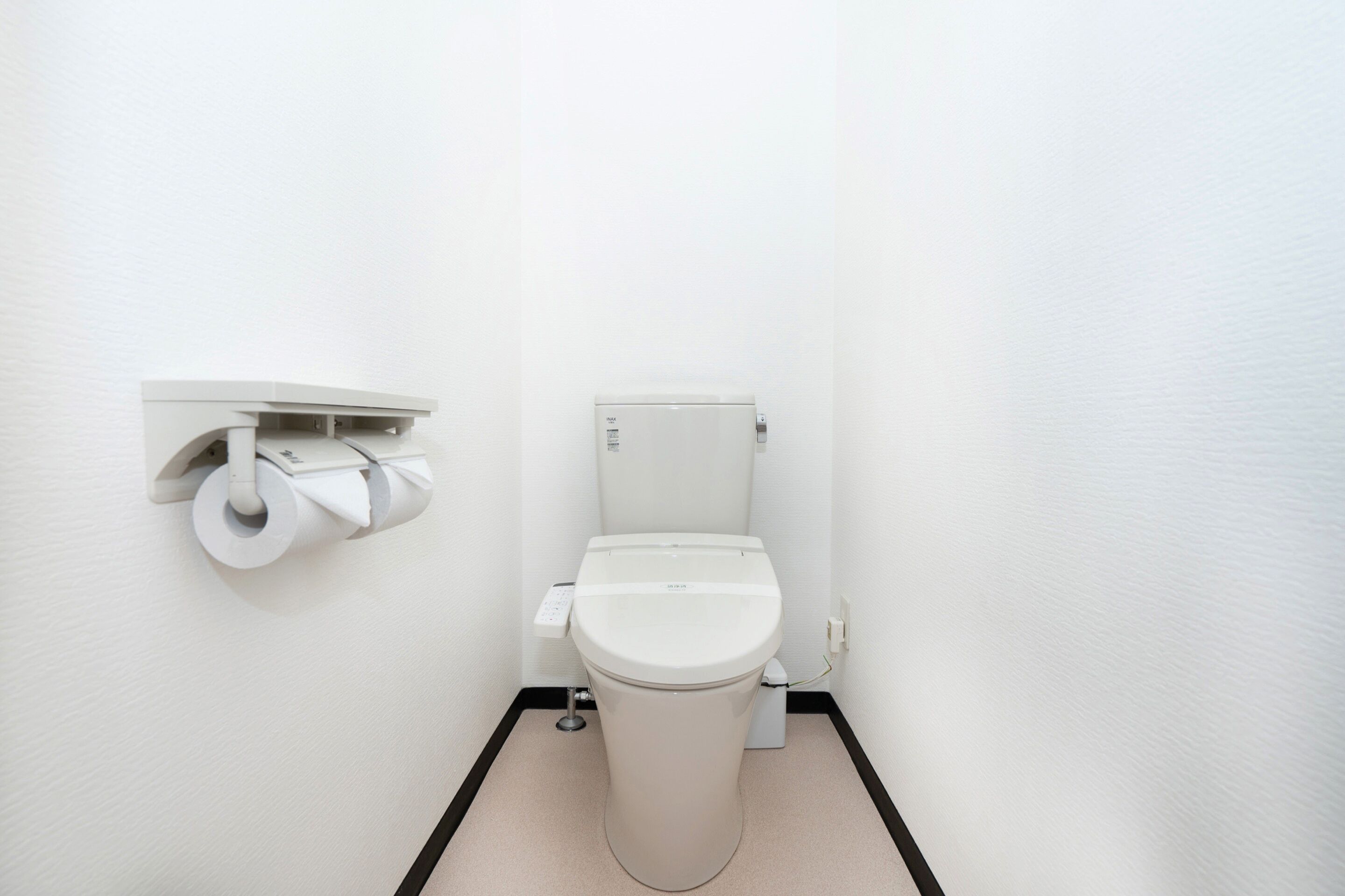 A small, clean bathroom with a toilet, a toilet paper holder, and a trash bin.
