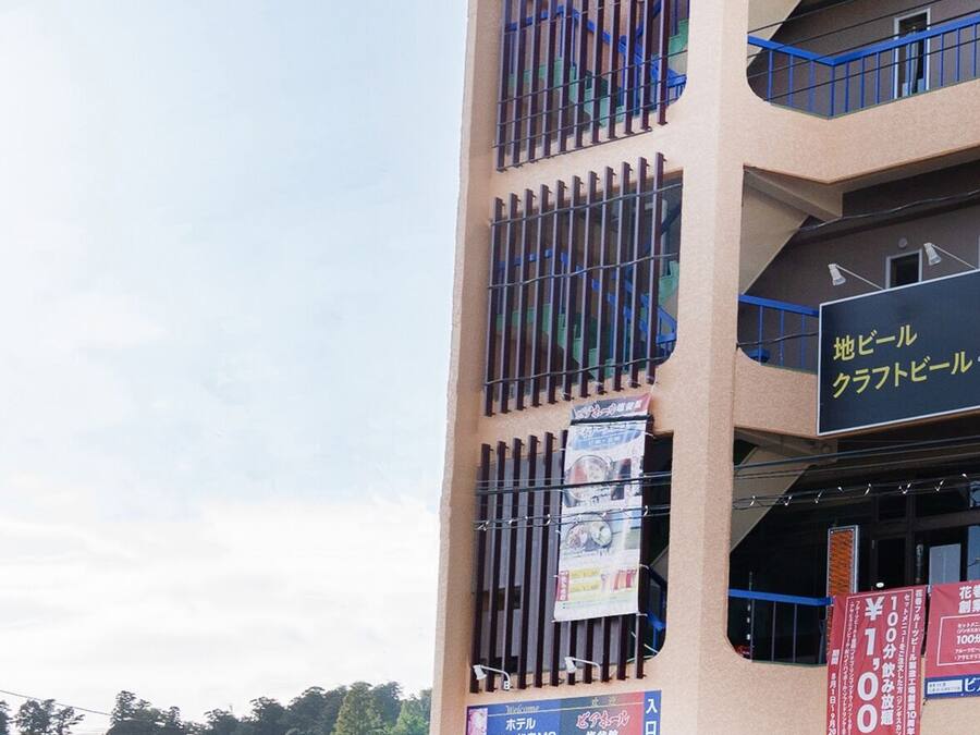 A multi-story building with a beige facade, multiple balconies, and various signage indicating different businesses.