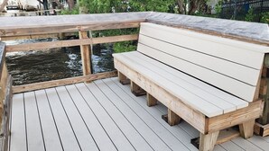 Une terrasse en bois avec un banc donnant sur une étendue d’eau.
