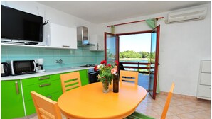 A kitchen with a dining table, chairs, a TV, and a view of the outdoors. - Apartment house by the sea (Nin)