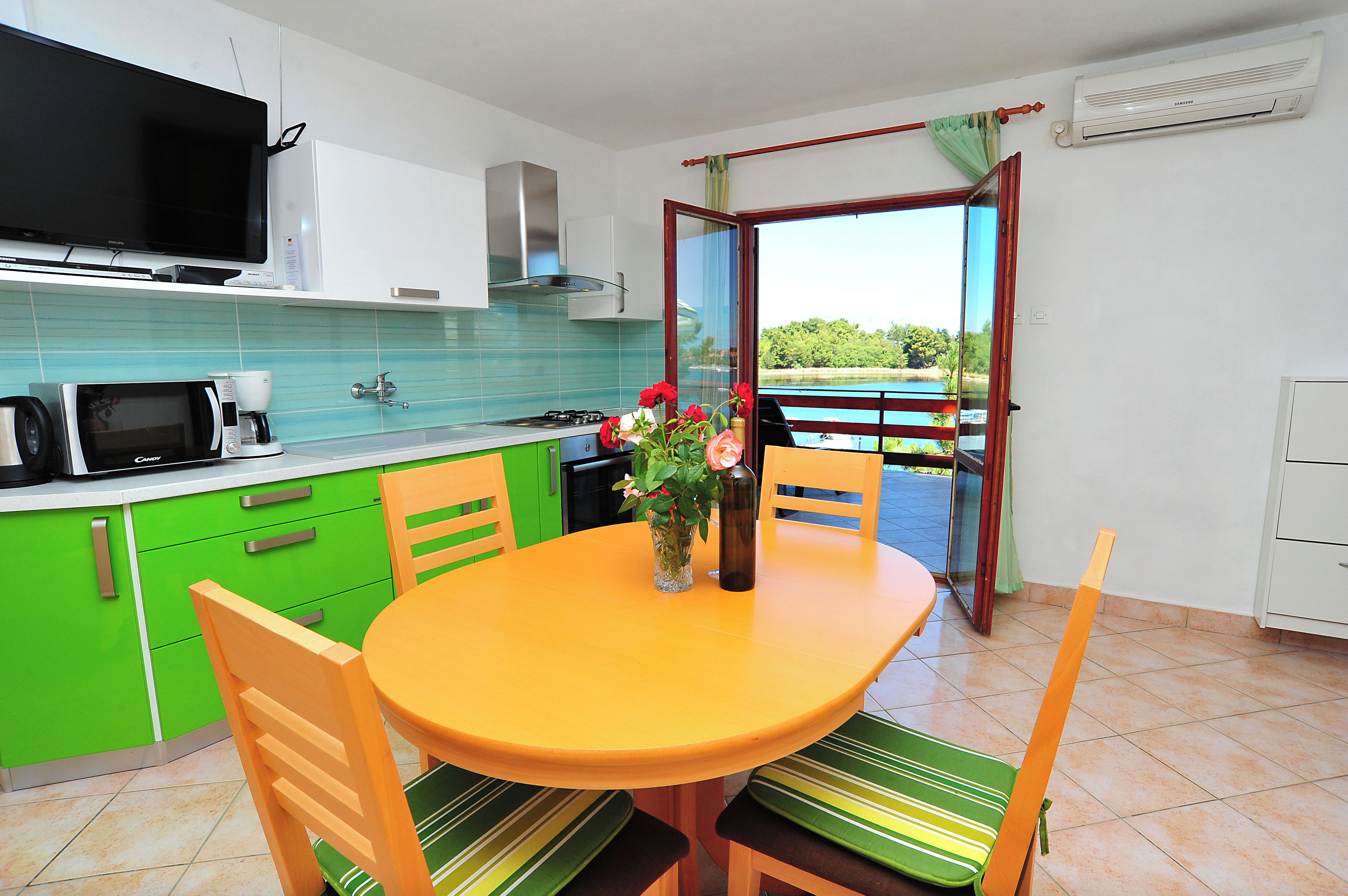 Una cucina con tavolo, sedie, televisione e vista sull'esterno.