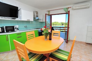 Una cocina con una mesa de comedor, sillas, un televisor y vistas al exterior.