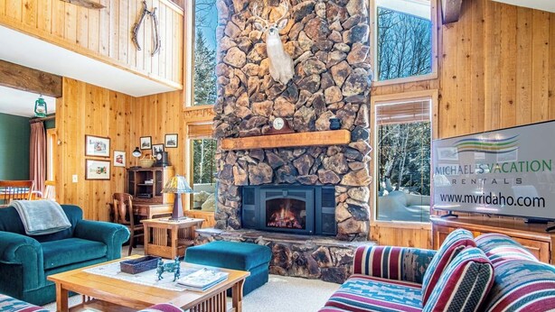 Ein gemütliches Wohnzimmer mit Kamin aus Stein, Holzwänden und einem Schild für Michael's Vacation Rentals.