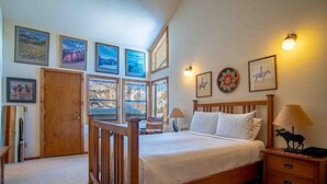 Ein Schlafzimmer mit einem hölzernen Bett, einem Nachttisch, einer Lampe und gerahmten Bildern an der Wand.