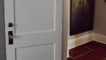 Une porte blanche portant le numéro 2, un tableau accroché au mur et un tapis à motifs.