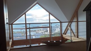 Una habitación con techo inclinado, ventanas amplias y vistas a la costa.