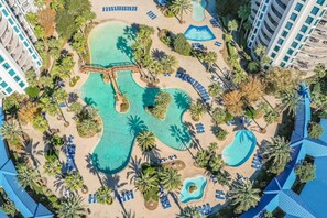 Oversigtsbillede af et resort med flere swimmingpools, palmer og strandområder.