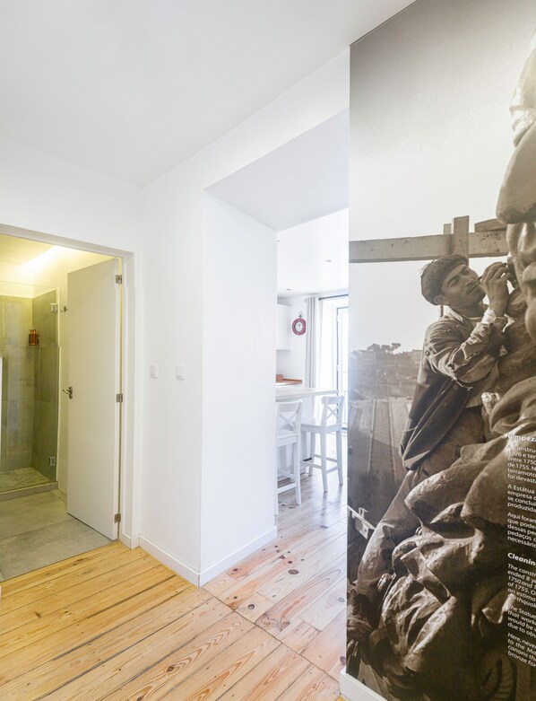 Un interior moderno con piso de madera, paredes blancas y una puerta de cristal que da a la zona de la ducha.