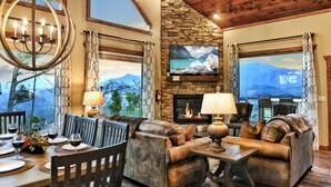 A cozy living room with a stone fireplace, leather sofas, and a large TV mounted on the wall.