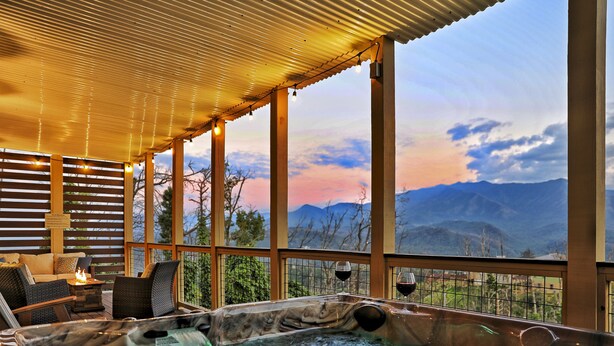 A hot tub area with a view of mountains, a fire feature, and a seating area with a view.