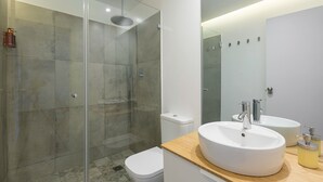A modern bathroom with a glass-enclosed shower, two sinks, and a toilet.
