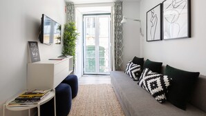 A modern living room with a sofa, a coffee table, a flat-screen TV, and artwork on the walls.