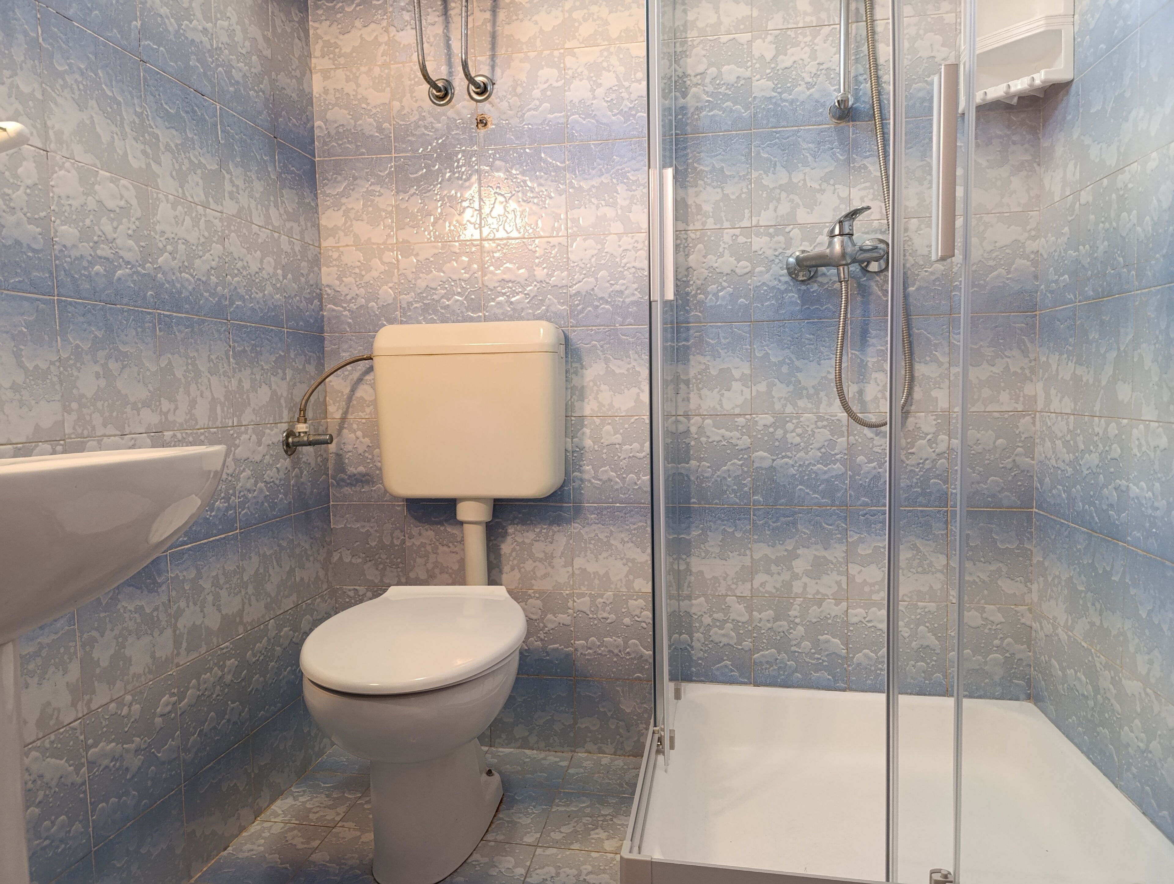 A bathroom with a toilet, sink, and shower.