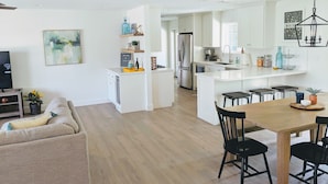A modern kitchen with white cabinetry, a central island, and a dining area with a wooden table and black chairs.