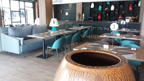 Un interior de restaurante moderno con sofás grises, sillas color turquesa y mesas de madera.