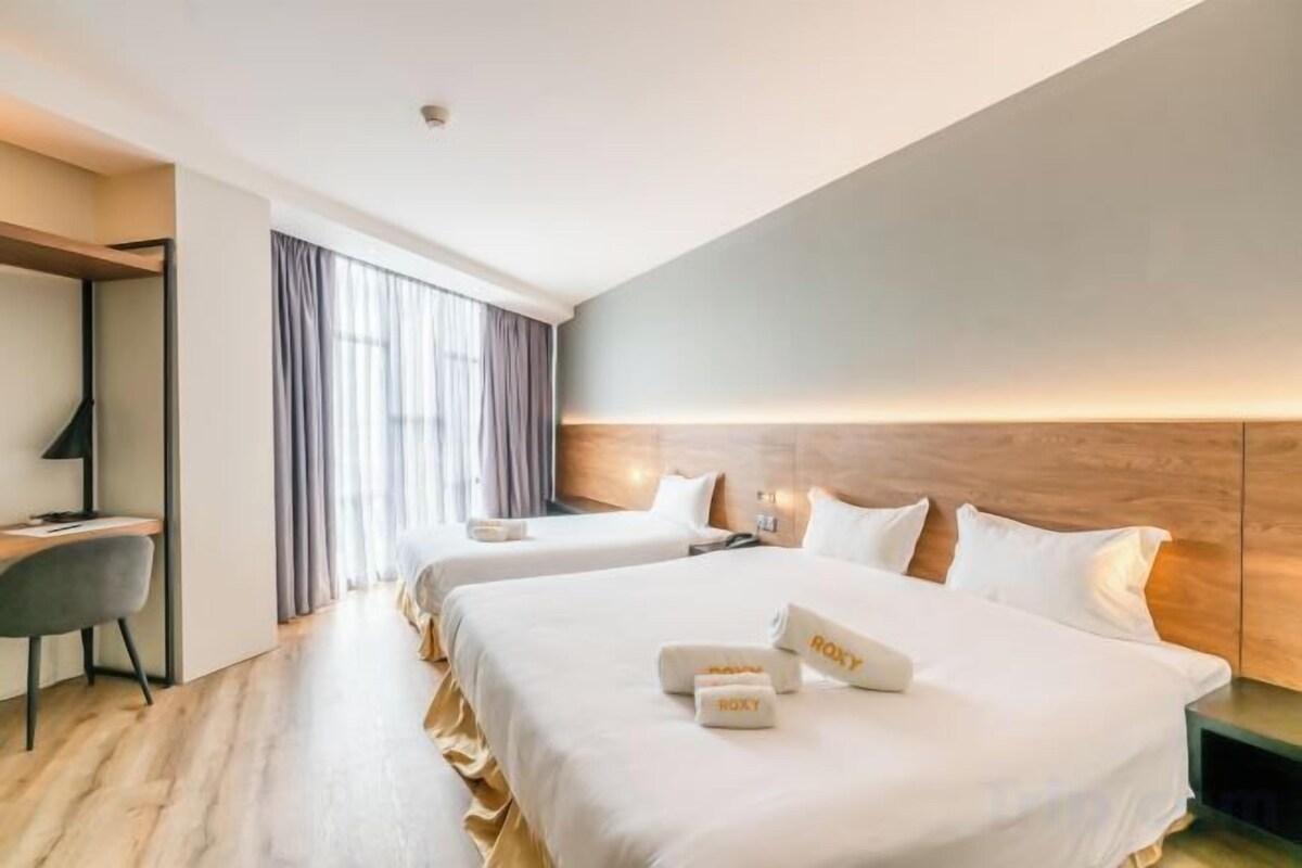 Habitación de hotel con dos camas, un escritorio y una silla.
