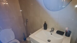 Un bagno con lavandino bianco, uno specchio, un water e una doccia.