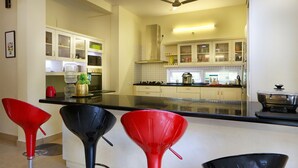 A modern kitchen with white cabinets, a black countertop, and red bar stools.
