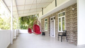 A covered outdoor area with a stone wall, a door, and a swing chair.