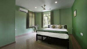 A bedroom with a bed, an ironing board, and a ceiling fan.
