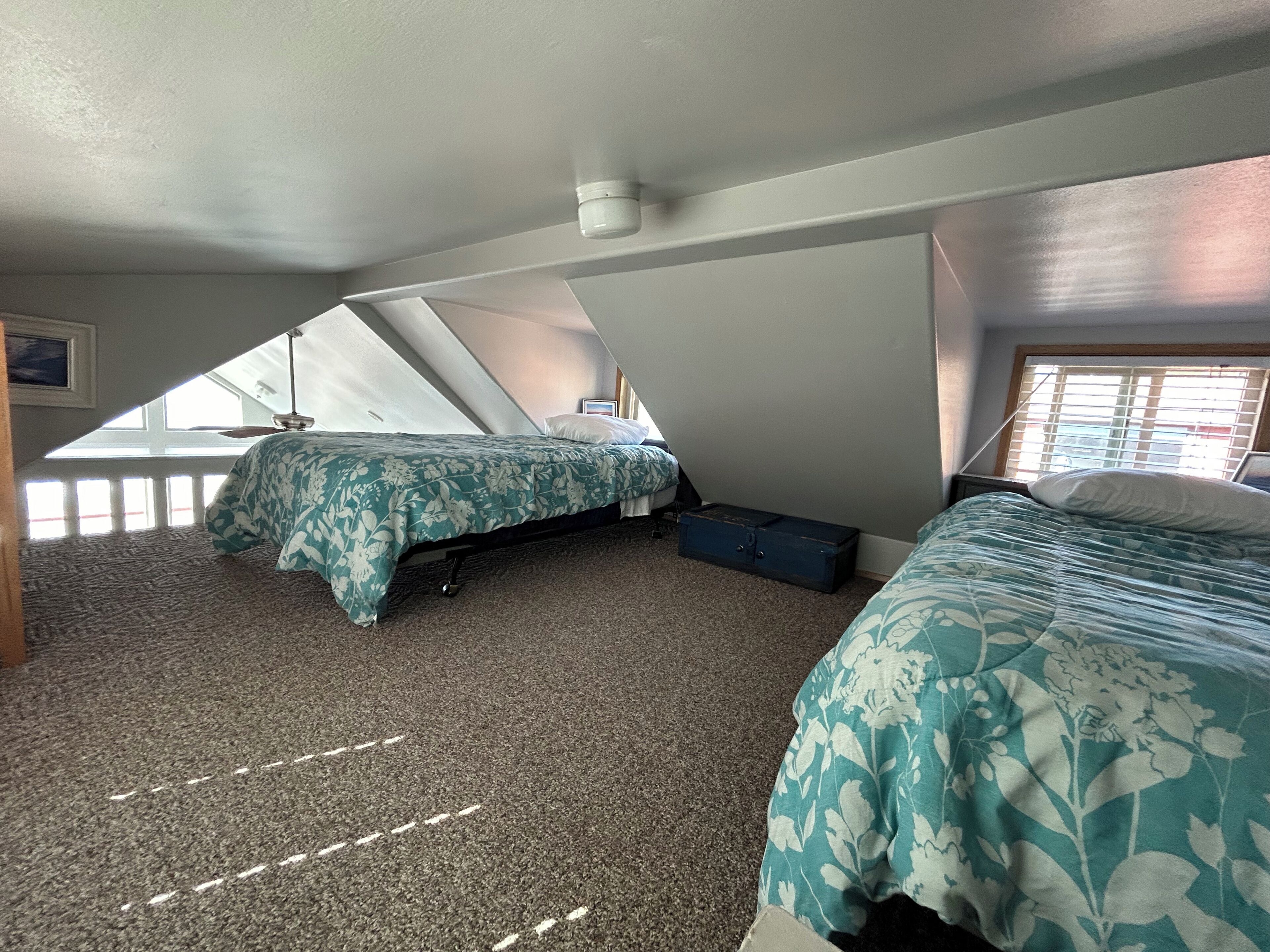 A bedroom with two beds, a window, and a ceiling fan.