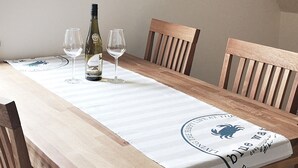 A dining table with a white tablecloth, wooden chairs, and a bottle of wine. - Apartments Möwe - Apartment upper floor with lake view (Lembruch)