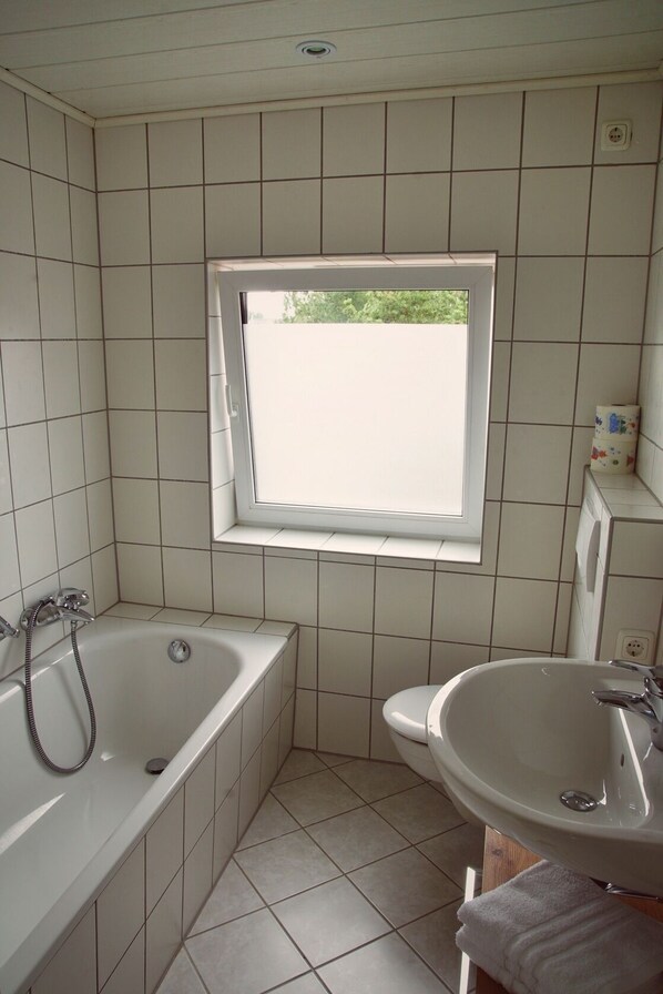 Ein Badezimmer mit einer Badewanne, einem Waschbecken und einem Fenster.