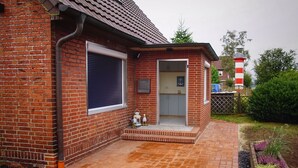 A brick house with a small porch, a garage door, and a mailbox. - Apartments Möwe - Apartment upper floor with lake view (Lembruch)