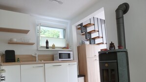Een moderne keuken met witte kastjes, een magnetron en een houtkachel.