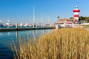 A marina with boats, a lighthouse, and a building with a red and white striped awning.