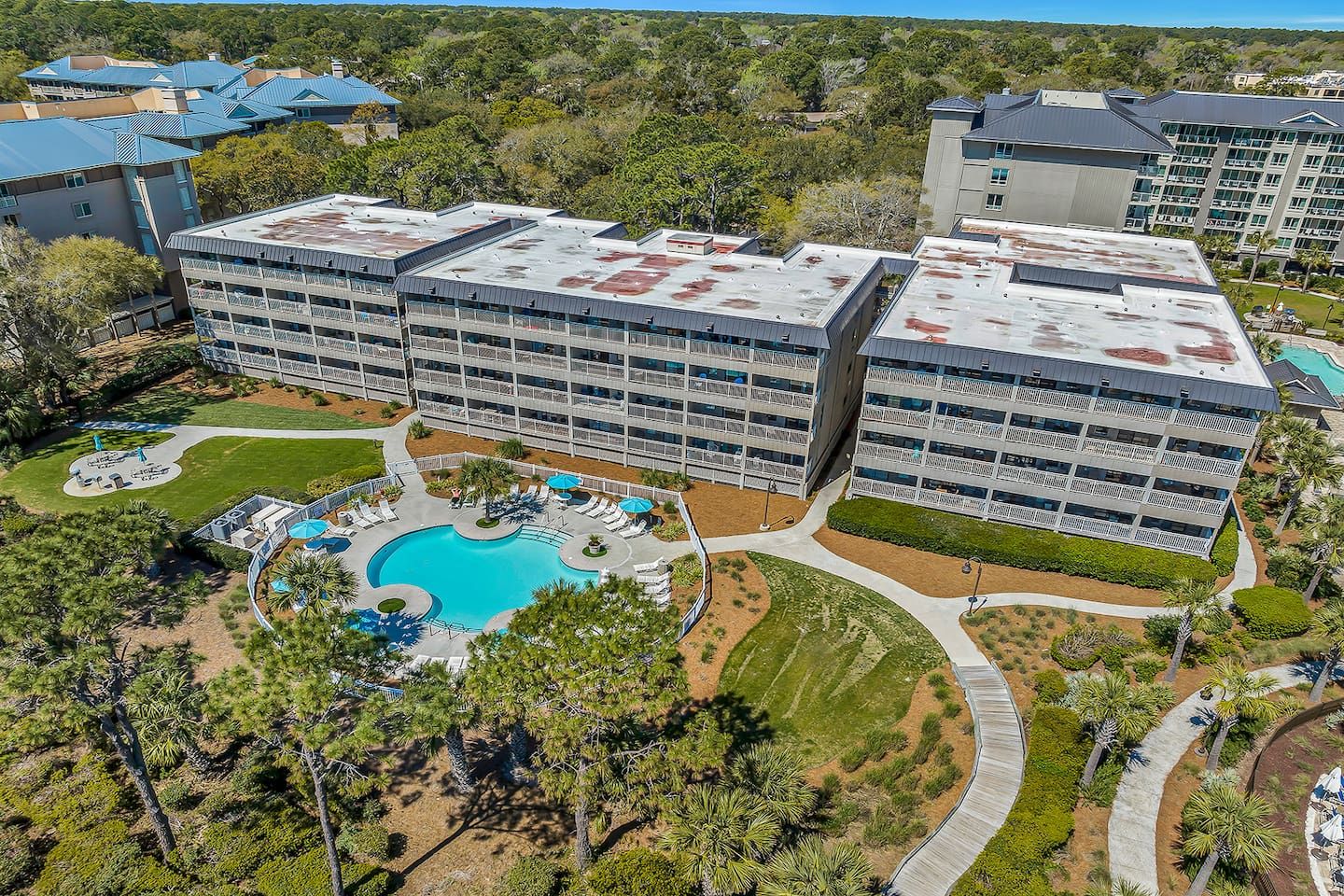 Ein mehrstöckiges Hotel mit Dachpool und angelegten Grünflächen.
