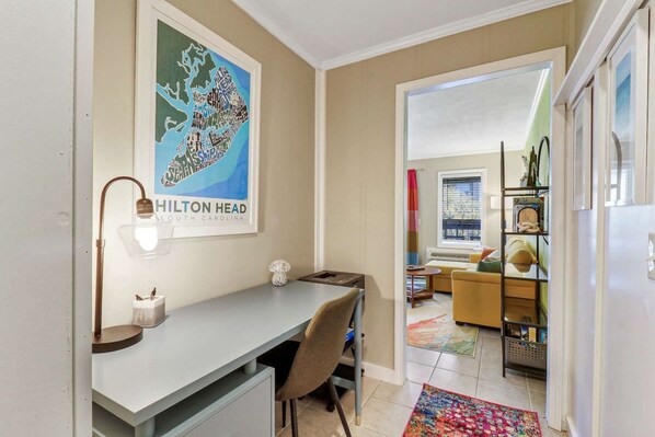 A modern hotel room with a desk, chair, and a poster of Hilton Head, South Carolina.