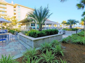 An outdoor patio area with a stone wall, seating, and palm trees.