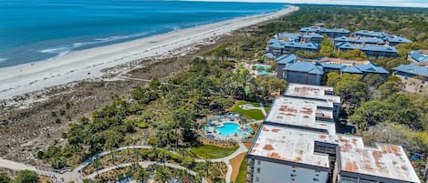 Un complejo turístico con varias edificaciones, frente a la playa y un área de piscina.