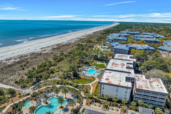 A resort with multiple buildings, a beachfront, and a swimming pool area.