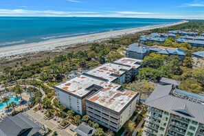A resort with multiple buildings, a pool area, and a beach view.
